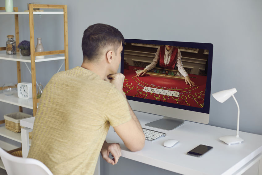 Online casino. A man makes bets online casino video chat casino cards poker roulette.