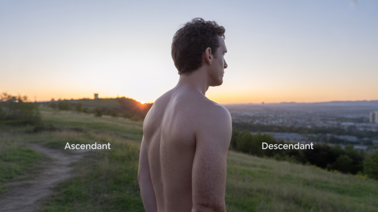 Personne observant un lever de soleil sur une ville depuis une colline, symbolisant l’ascendant et le descendant en astrologie.