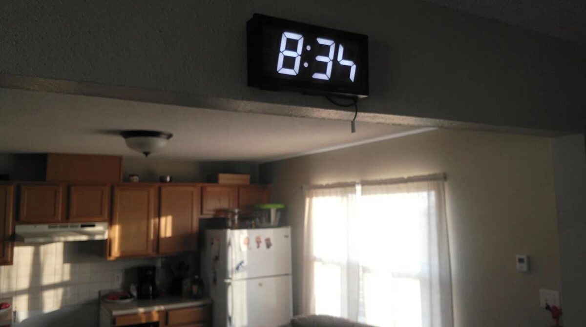 Une horloge numérique sur un mur de cuisine en fin de journée — 15h51, heure inversée